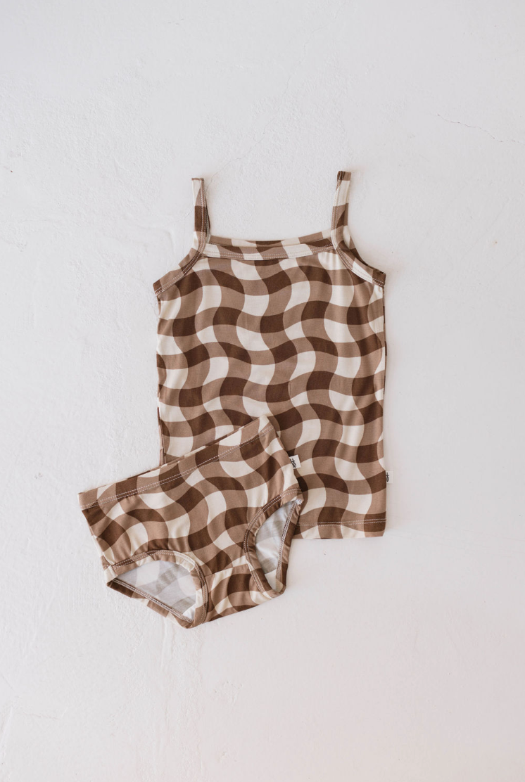 A matching set of children’s clothing is displayed on a white background. The Basic Bamboo Tank | Groovy Gingham by forever french baby is crafted from breathable bamboo fabric and includes a sleeveless tank top paired with shorts, both adorned in a stylish checkered pattern featuring shades of brown and beige.