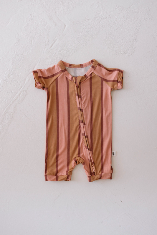 The Shortie Bamboo Zip | Boardwalk by forever french baby lies flat on a white surface, featuring vertical stripes in shades of pink and brown. With short sleeves and pant legs, it boasts a front zipper running from the neckline to the crotch. Made from hypo-allergenic materials, this romper ensures your baby stays comfortable all day.