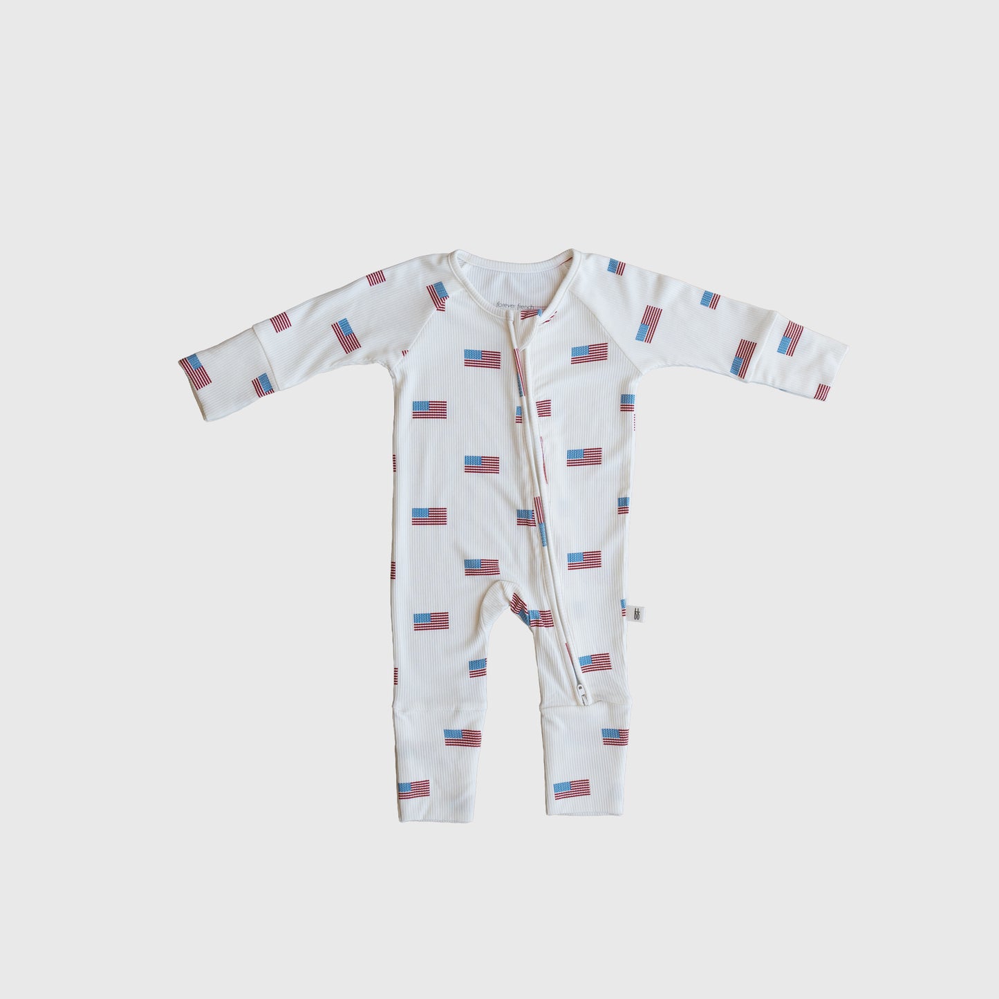 The Bamboo Zip Pajamas | Americana Ribbed by forever french baby is a white hypoallergenic baby onesie with a front zipper and an all-over small American flag pattern, shown flat on a plain white background.