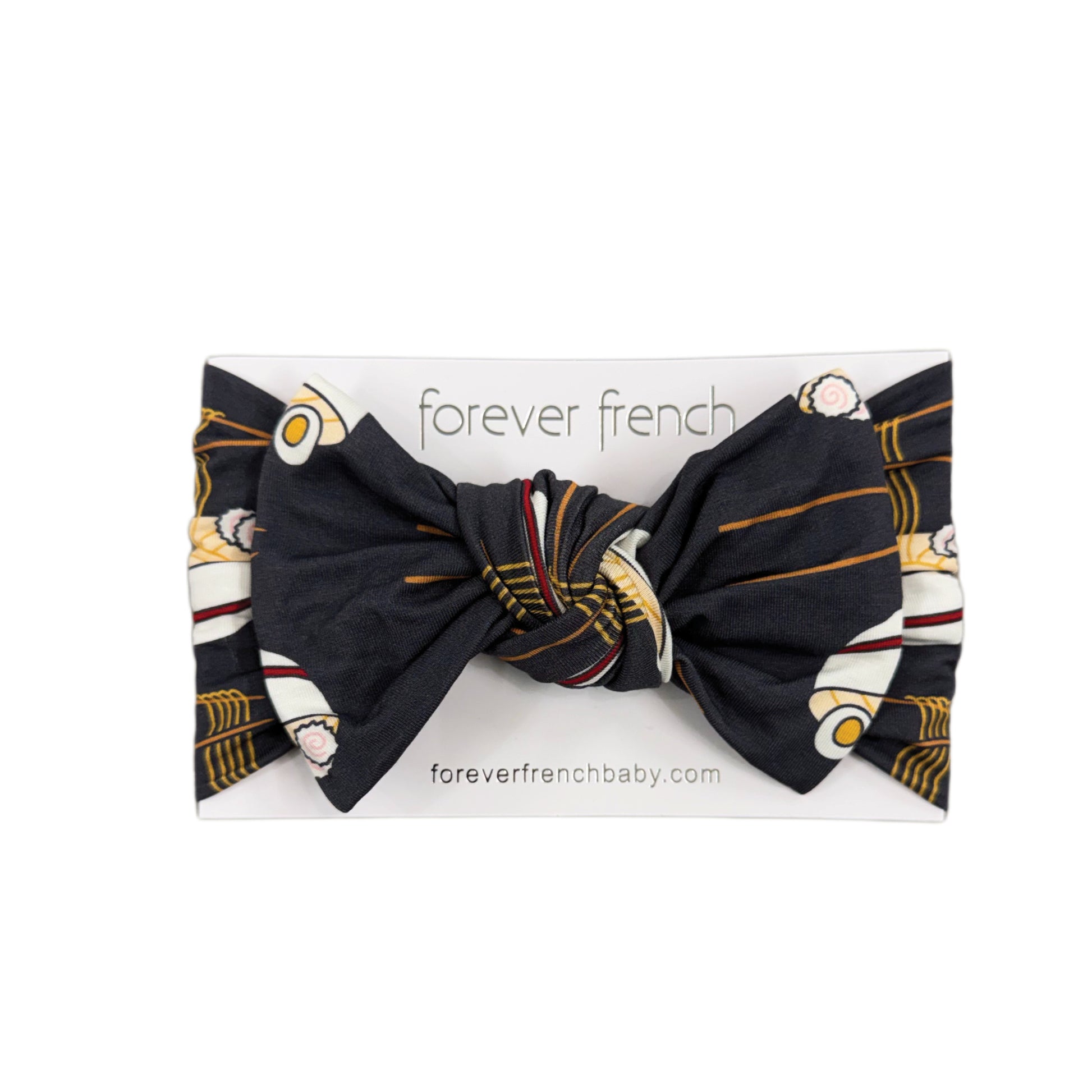 The Bamboo Head Wrap | Ramen by forever french baby is a knotted black baby headband with a retro car print in white and yellow, displayed on branded packaging.