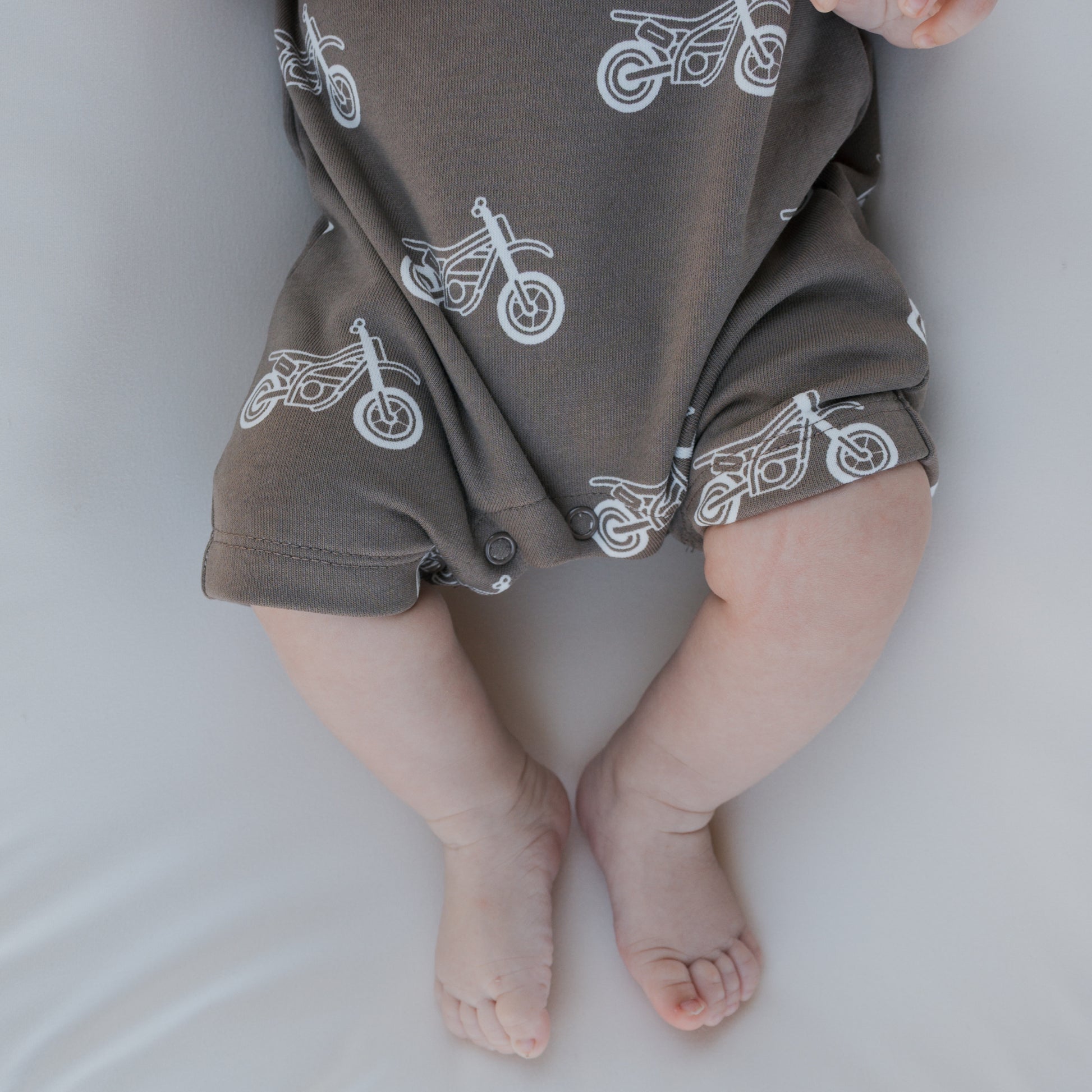 A close-up of a baby wearing the forever french baby French Terry Romper | Dirt Bike, featuring dirt bike prints—a cozy and stylish choice for newborns.