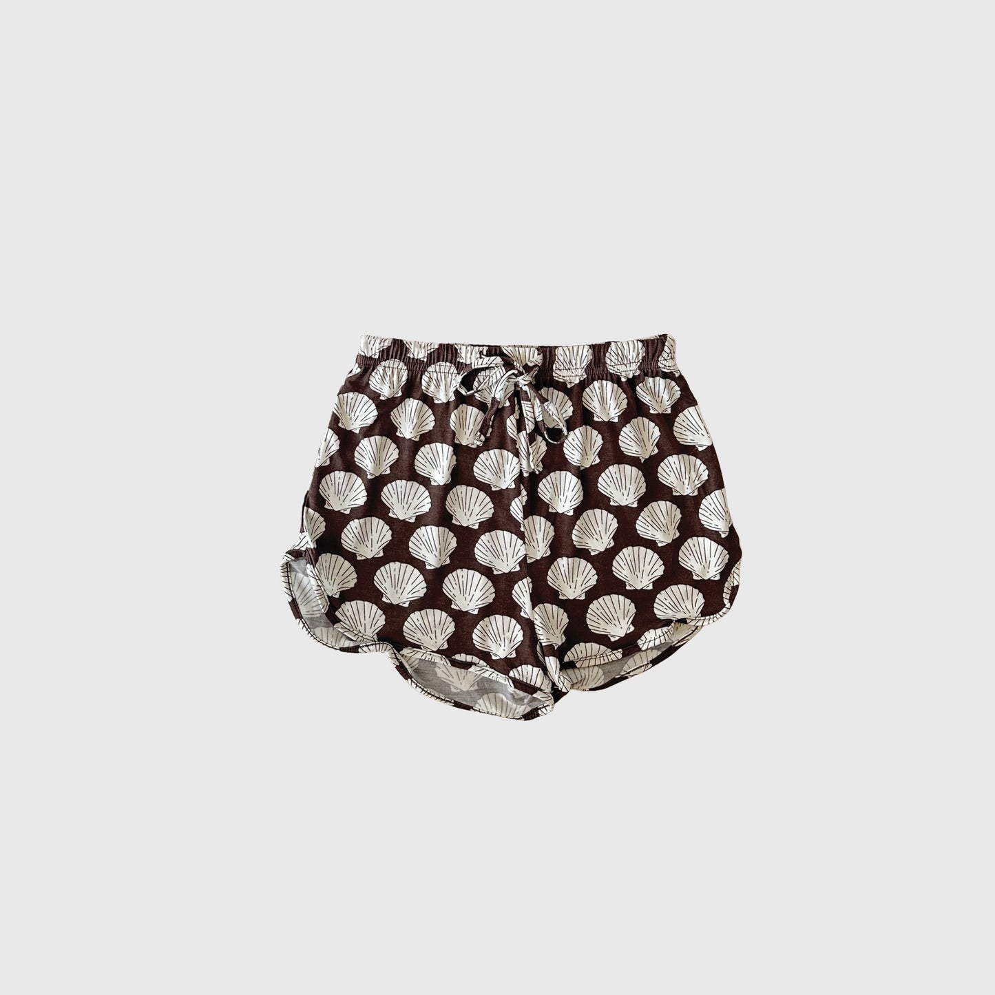 The Girl's Bamboo Short Set | Seashells by forever french baby features brown shorts with a white seashell print, an elastic waistband, and drawstring. Made from hypoallergenic, breathable bamboo fabric. Shown on a plain light background.