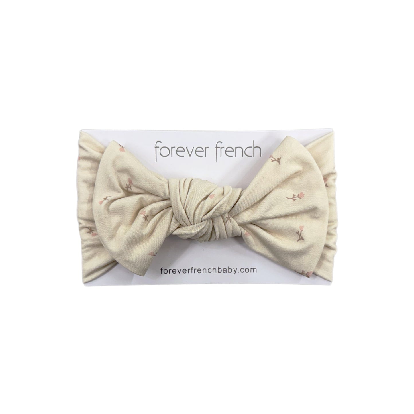 The Bamboo Head Wrap | Lucy by forever french baby is a cream floral baby headband with a large knotted bow, crafted from soft bamboo and displayed on a branded "forever french baby" card.