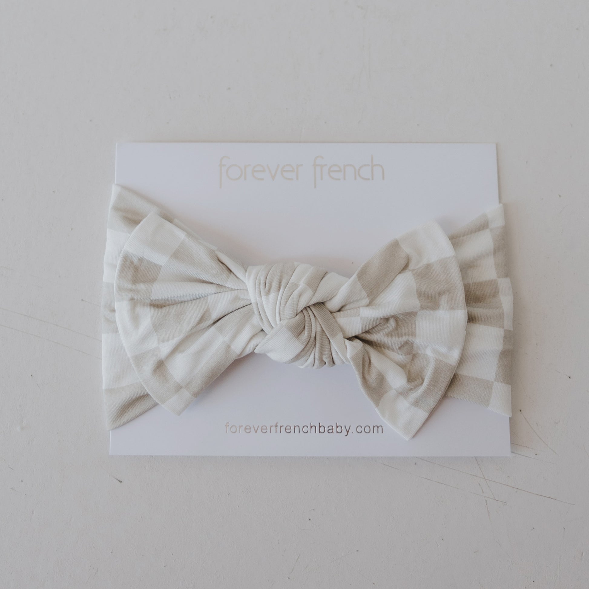 The Bamboo Head Wrap | Checkerboard from forever french baby is shown in beige and white on a white card labeled "forever french," with "foreverfrenchbaby.com" printed below.