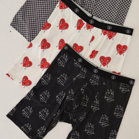 Three pairs of forever french baby Men's Bamboo Boxers are displayed: black with white flaming hearts, white with red sad girl hearts, and gray street micro check—available in a convenient 3-pack.