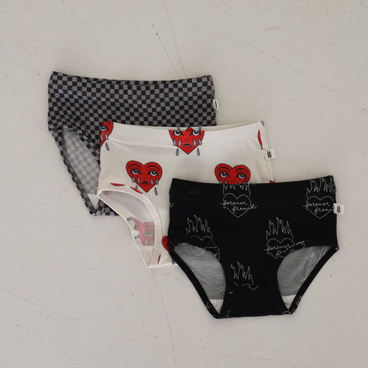 Three pairs of girl's bamboo briefs by forever french baby—Flaming Hearts, Sad Girl, & Street Micro Check—laid flat. Hypoallergenic and comfy for all-day wear.