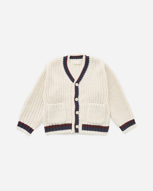 The Rylee + Cru Collegiate Cardigan in Natural is a cream-colored V-neck sweater featuring navy and burgundy trim on the collar, cuffs, and hem. Accented with unique mango wood buttons and finished with two front pockets for a refined collegiate style, the cardigan is displayed laid flat against a white background.