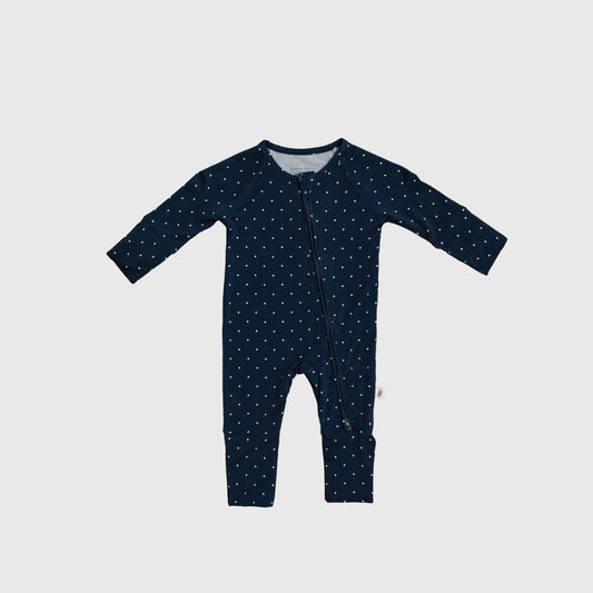 The forever french baby Bamboo Zip Pajamas | Emery is a navy blue, long-sleeve romper with legs, crafted from hypo-allergenic material and decorated with small white polka dots. It features an angled zipper from neck to left leg.