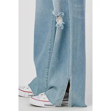 A close-up of the High Rise Skater Jeans in Medium Wash by I&M JEAN, INC., showcasing frayed tears and a side slit at the hem, complements white sneakers flawlessly.