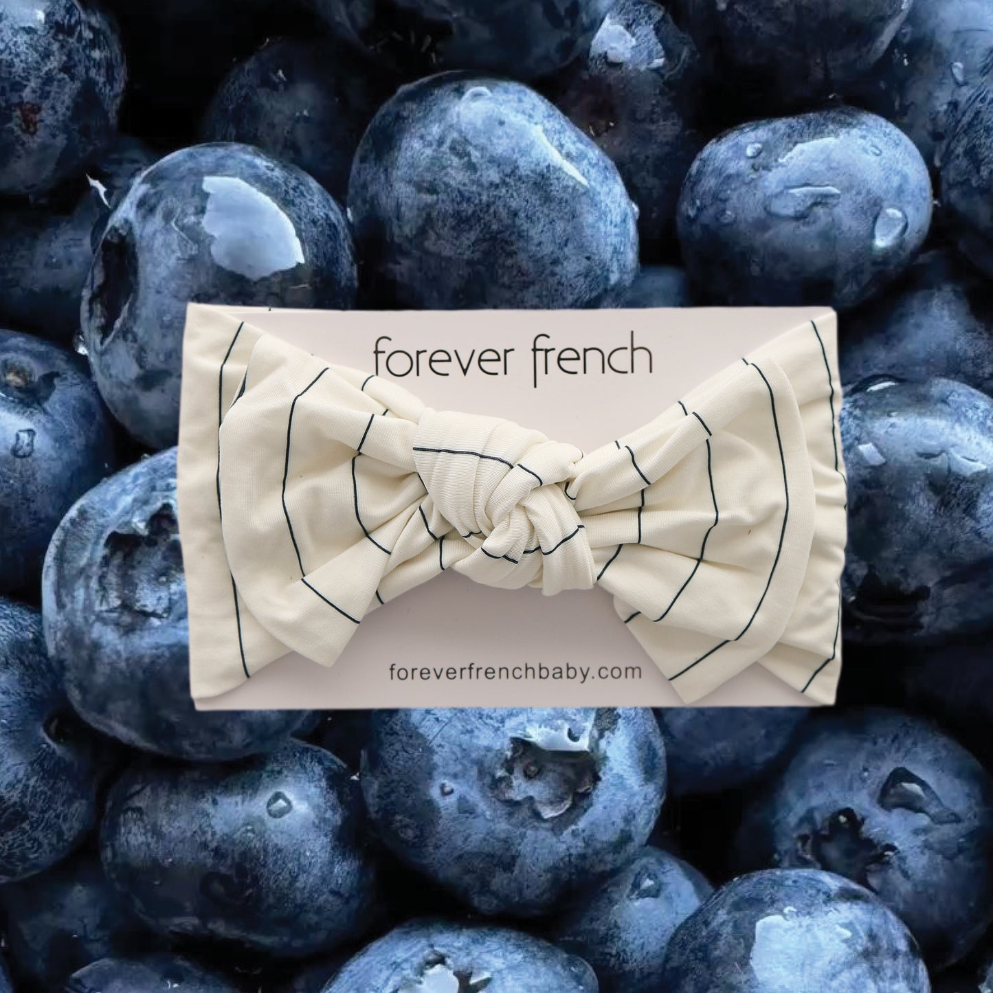 A cream-colored, striped Bamboo Head Wrap | Jack from forever french baby is displayed on a card, set against fresh blueberries.