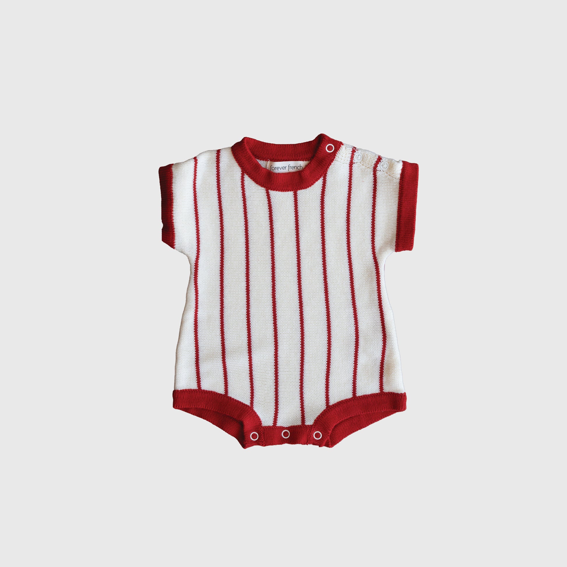 The Knit Romper | Picnic Pinstripe by forever french baby features red and white vertical stripes, red trim, is made from 100% cotton, and includes snap buttons at the bottom for easy changing.