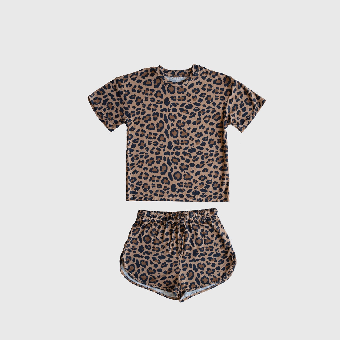 The Girl's Bamboo Short Set | Leopard by forever french baby features a short-sleeve T-shirt and drawstring shorts with an all-over brown and black leopard print, crafted from breathable bamboo, shown laid flat on a plain white background.