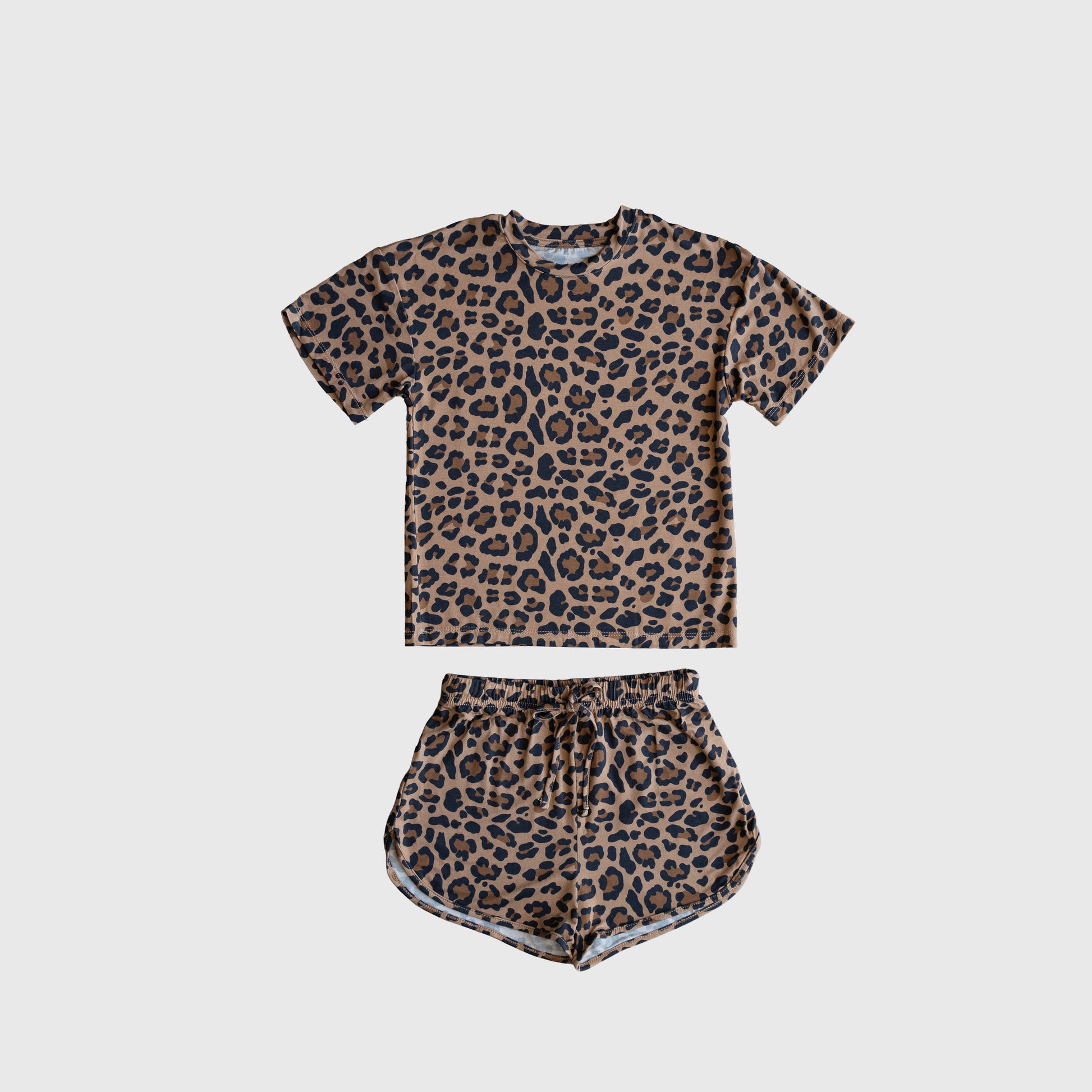 The Girl's Bamboo Short Set | Leopard by forever french baby features a short-sleeve T-shirt and drawstring shorts with an all-over brown and black leopard print, crafted from breathable bamboo, shown laid flat on a plain white background.