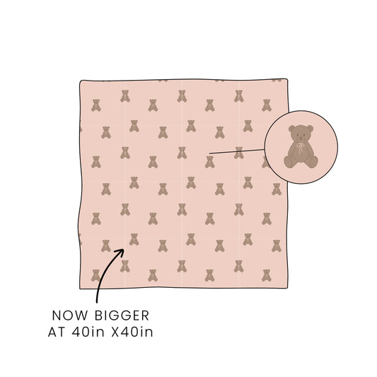 The forever french baby Bamboo Swaddle | Lottie is a soft, pink, hypoallergenic blanket with a teddy bear print. Shown in a 40in x 40in size, it's breathable and ideal for wrapping infants or children.