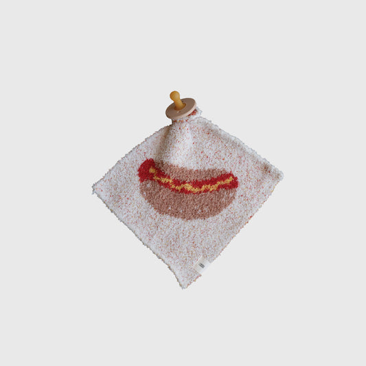 The Lovey | Hot Dog by forever french baby is a soft, square microfiber feather yarn baby lovey featuring a hot dog design, attached to a wooden pacifier and displayed on a plain white background.