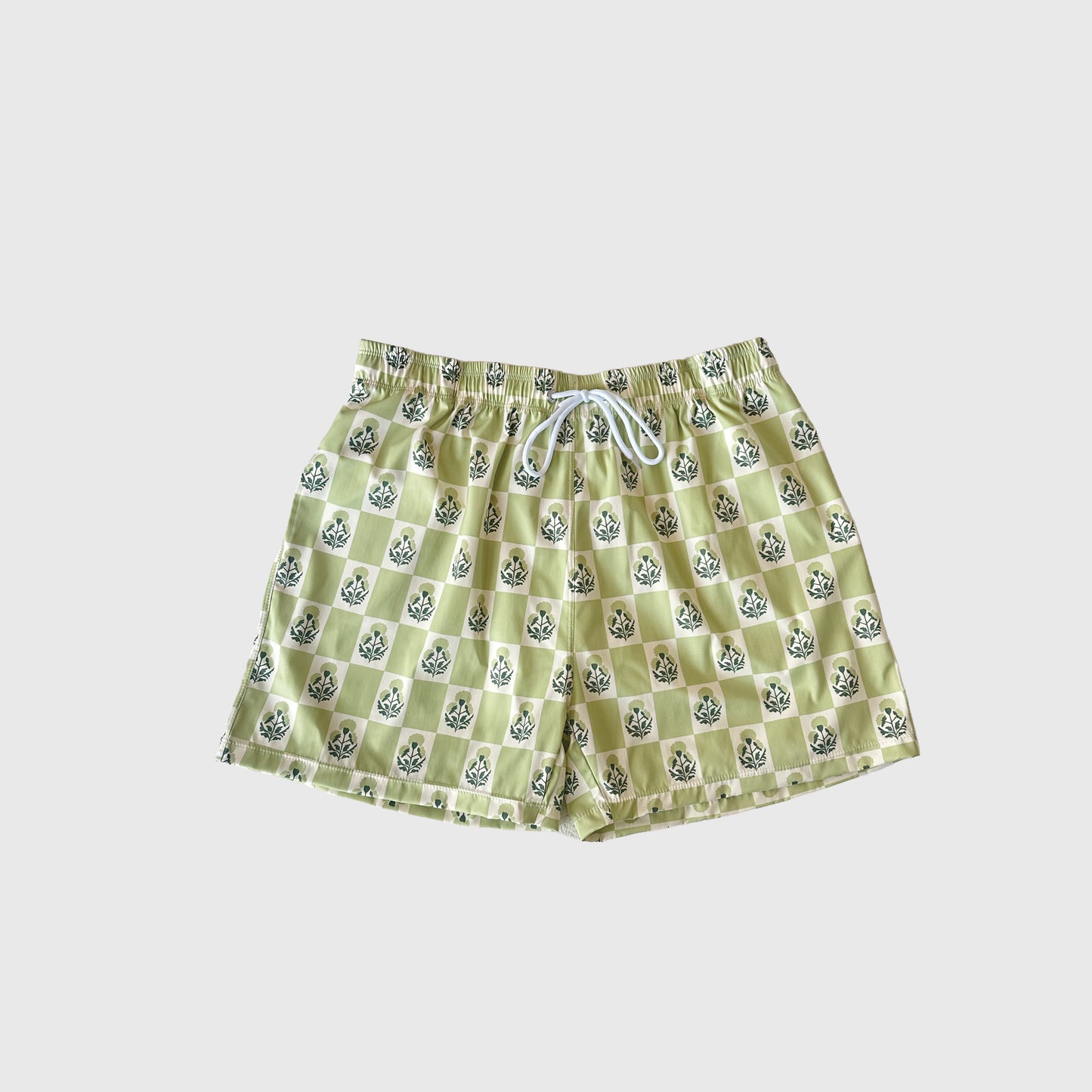 Men’s Board Short | Marigold Check by forever french baby features light yellow and green checker print with faces in each square, elastic waistband, white drawstring—all shown on a plain white background. Playful design meets Forever French style.