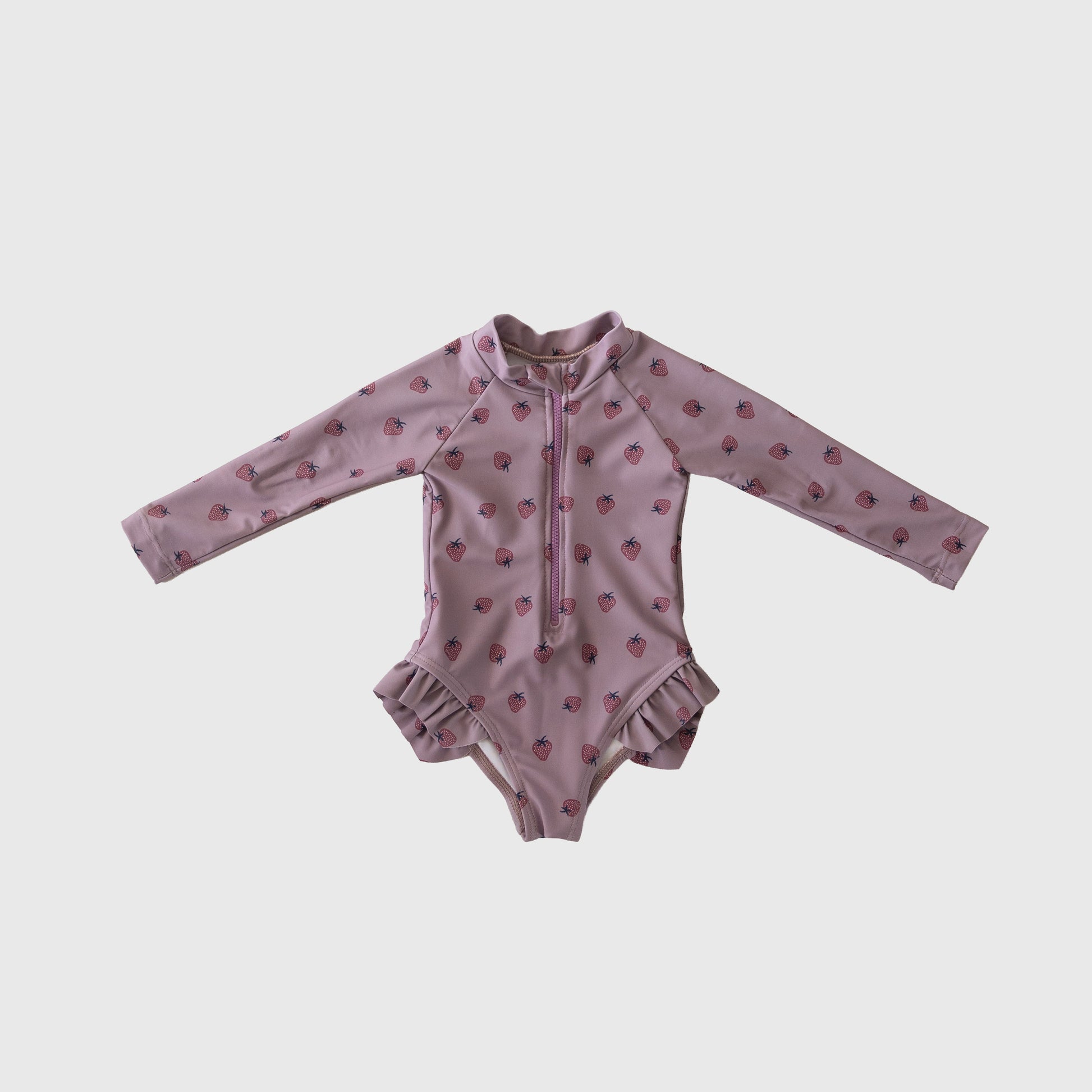 The Matilda Girl's Long Sleeve Swimsuit by forever french baby features a light pink one-piece with ruffled hips, front zipper, and a cute red strawberry pattern.