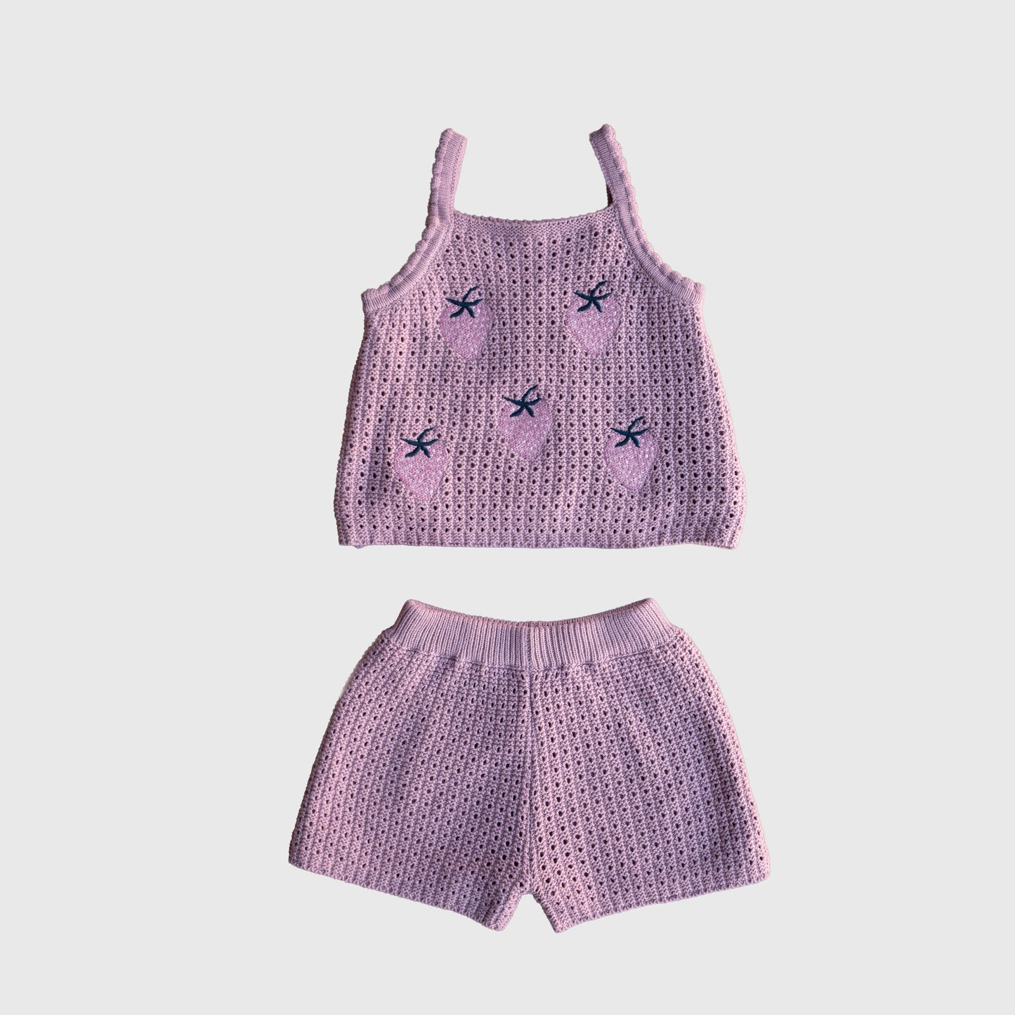 The Girl's Knit Short Set | Matilda by forever french baby is a two-piece pink crochet outfit for children, crafted from soft knit fabric. It features a sleeveless top with small embroidered strawberries and matching shorts, both displayed on a white background.