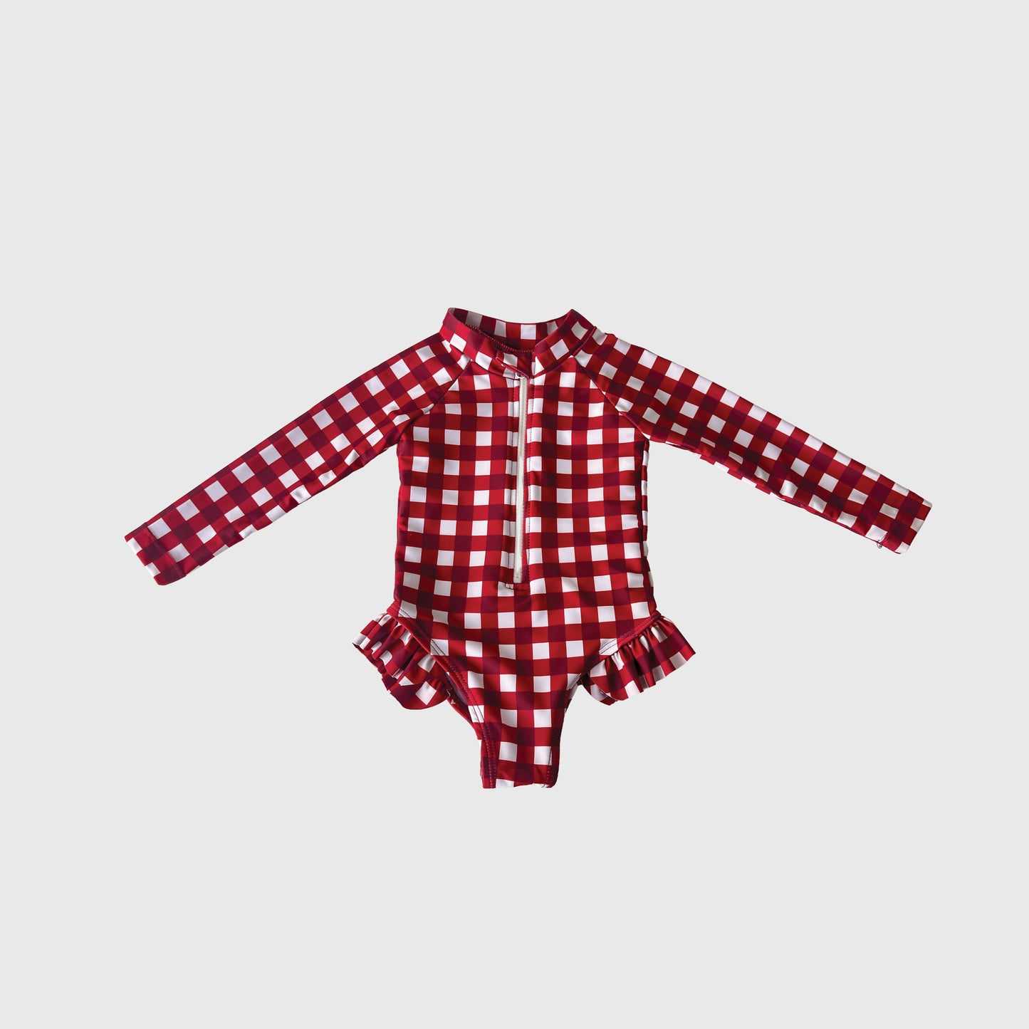 The Girl's Long Sleeve Swimsuit in Scarlet Gingham from forever french baby features a red and white plaid print, front zipper, and ruffle hip details—perfect summer swimwear, shown on a plain white background.