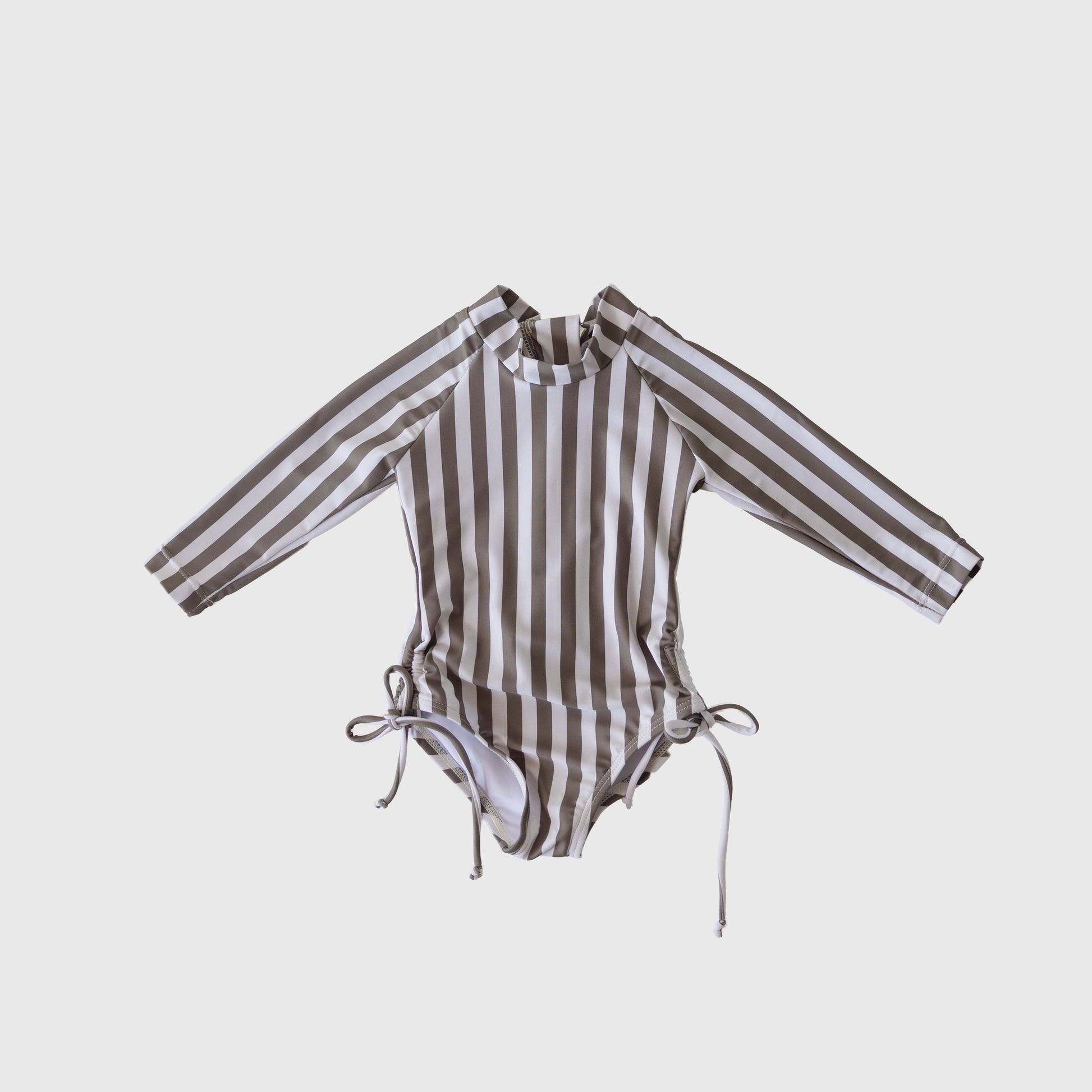 The forever french baby Girl's Long Sleeve Swimsuit in Olive Stripe features vertical olive and white stripes, a high neckline, long sleeves, and chic hip ties. This one-piece is shown against a plain white background.
