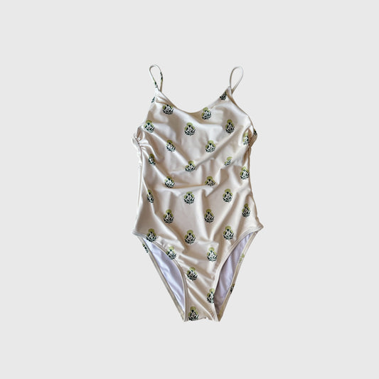 The Forever French Women's One Piece Swimsuit | Marigold features thin straps, a white base, and a repeating green and black floral pattern, shown on a plain light gray background.