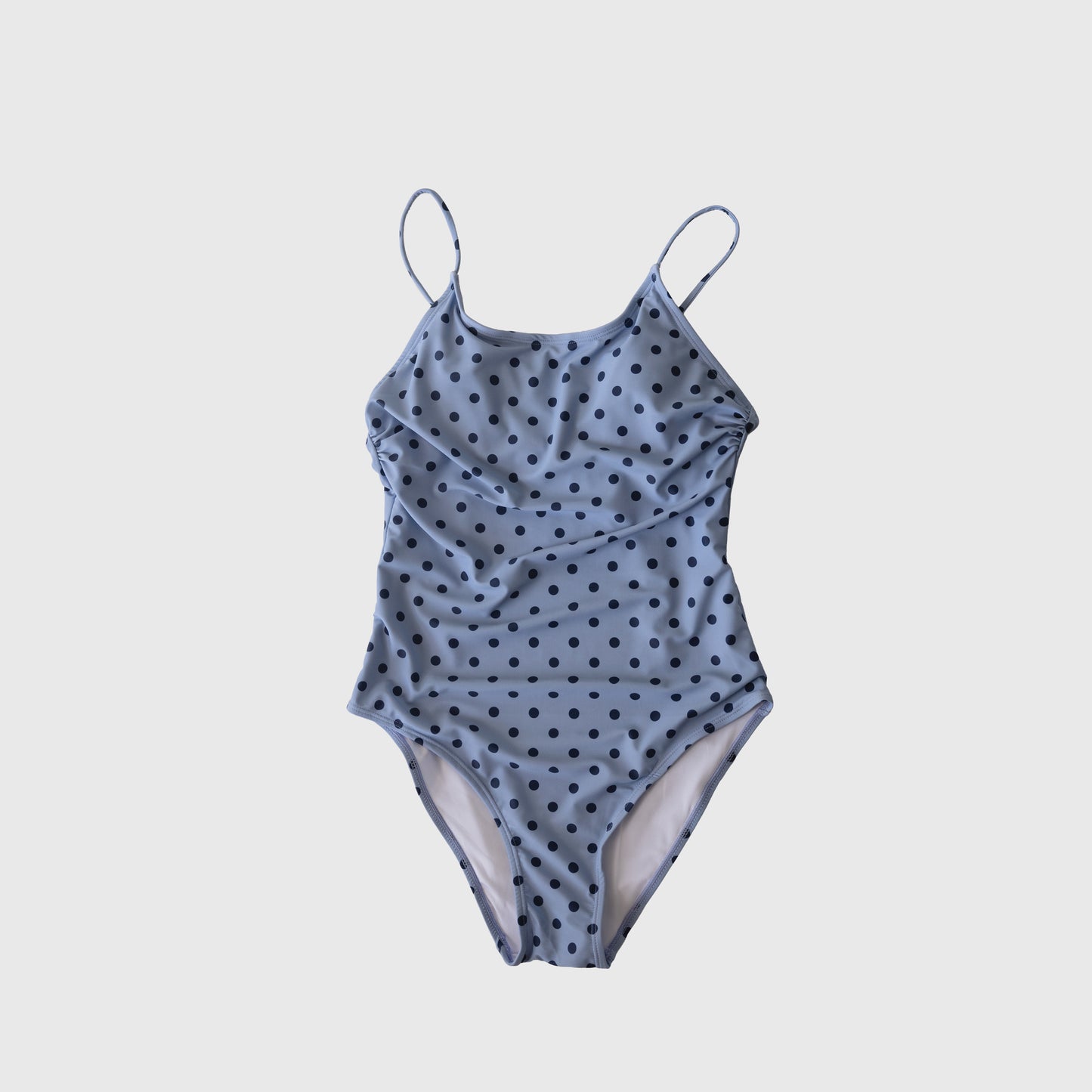 The Women's One Piece Swimsuit "Sully" by Forever French features a light blue design with thin straps and black polka dots, ideal for summer beachwear, displayed flat on a white background.