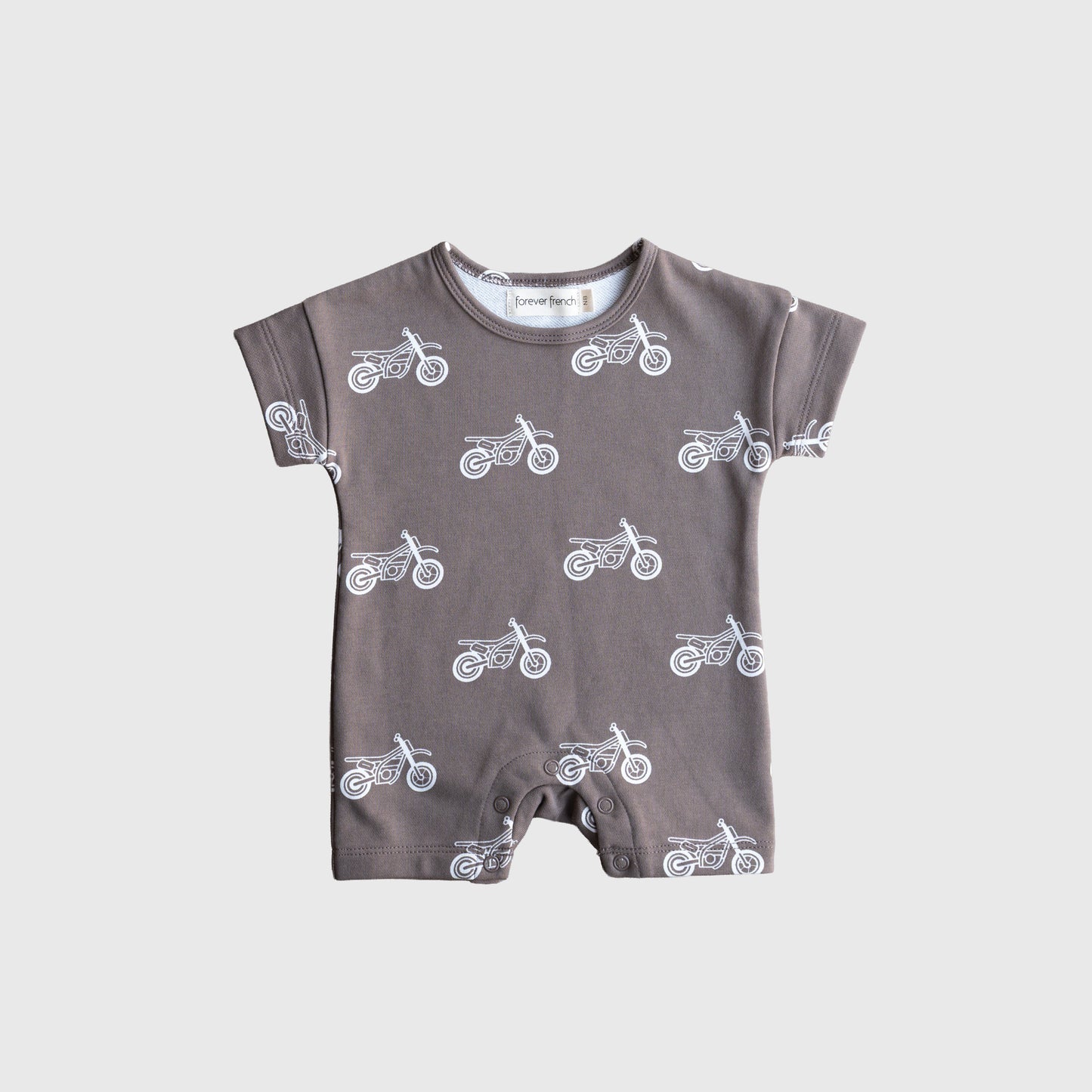 The French Terry Romper | Dirt Bike by forever french baby features short sleeves, soft cotton fabric, and a white motorcycle print on gray—snap-bottom with a round neckline. Perfect stylish comfort for newborns. Displayed on a plain light gray background.