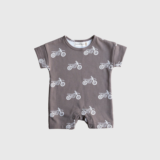 The French Terry Romper | Dirt Bike by forever french baby features short sleeves, soft cotton fabric, and a white motorcycle print on gray—snap-bottom with a round neckline. Perfect stylish comfort for newborns. Displayed on a plain light gray background.