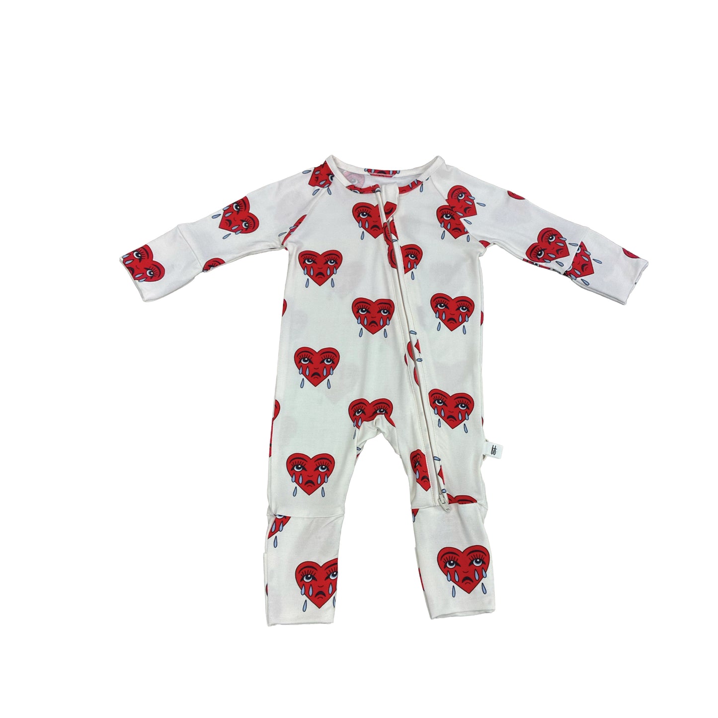 The Bamboo Zip Pajamas | Sad Girl by forever french baby is a white baby onesie with long sleeves, rollover cuffs, legs, and a diagonal neck-to-leg zipper. Features hypoallergenic fabric and red hearts with expressive faces and teardrops.