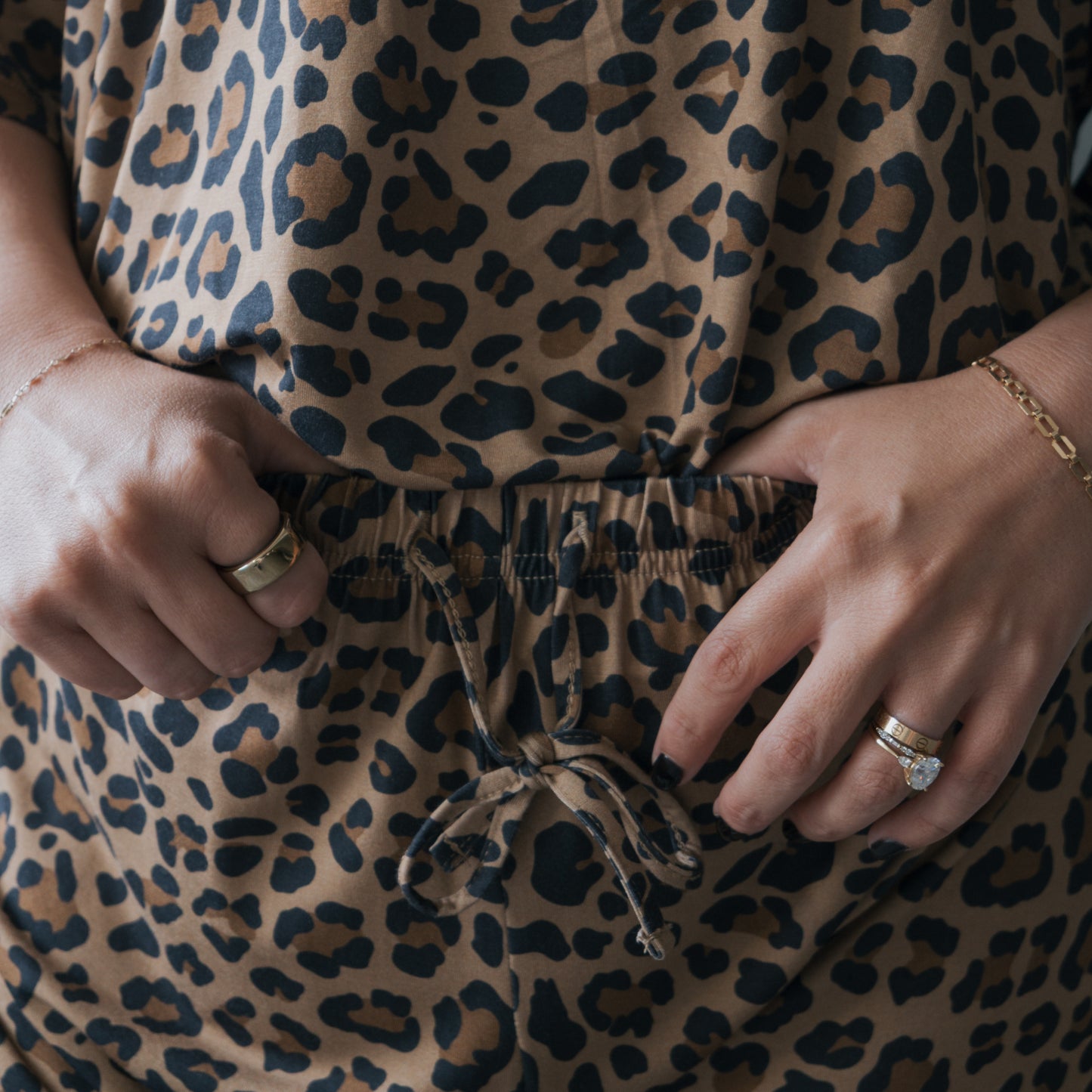A woman models the forever french baby Women's Bamboo Short Set in Leopard, accessorized with gold rings and bracelets. The hypoallergenic set features a waist drawstring and convenient pockets.