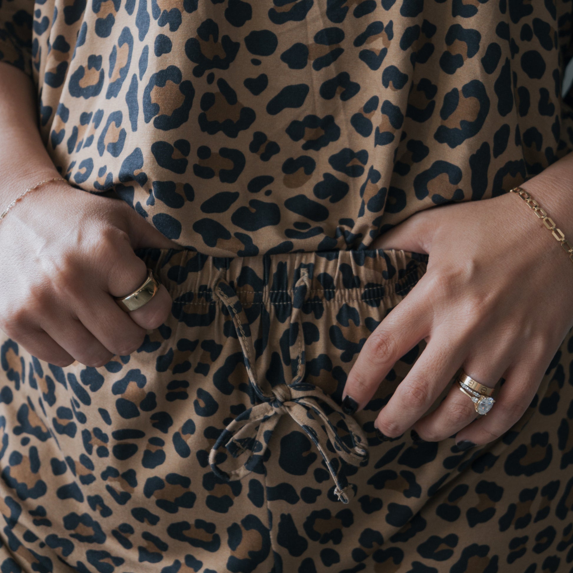 A woman models the forever french baby Women's Bamboo Short Set in Leopard, accessorized with gold rings and bracelets. The hypoallergenic set features a waist drawstring and convenient pockets.