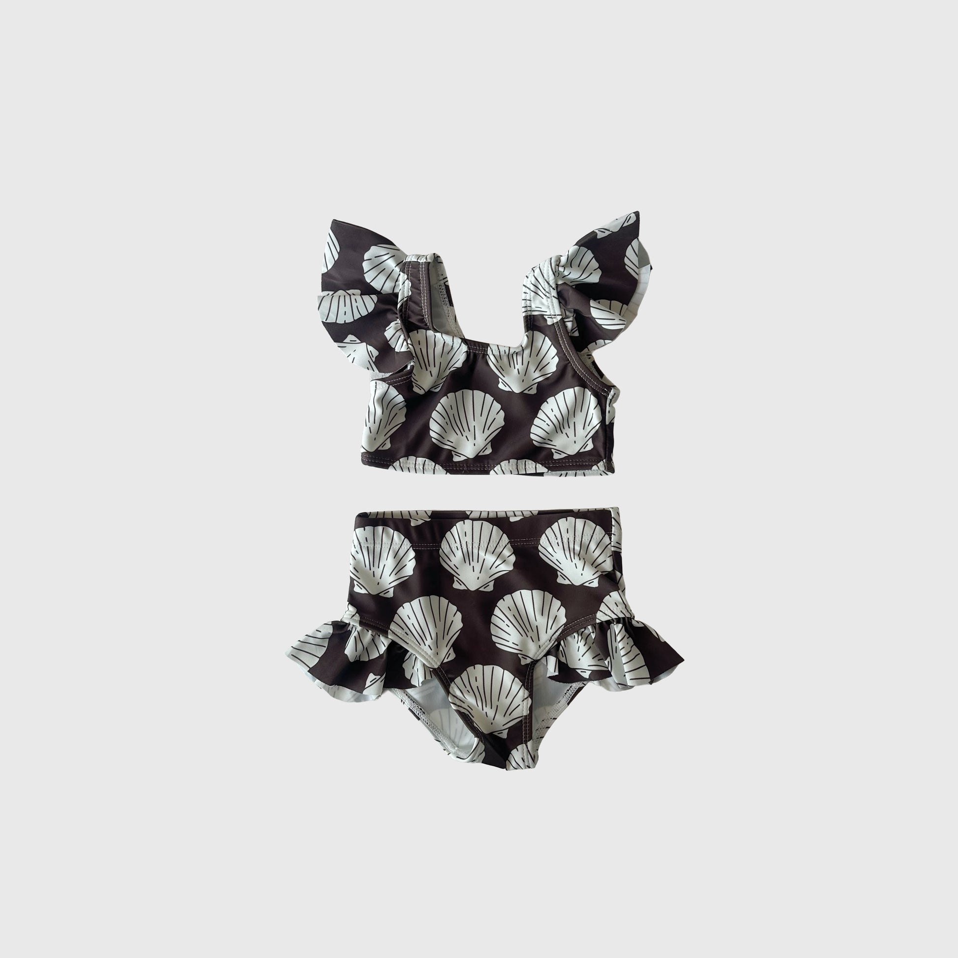 The Girl's Two Piece Swimsuit | Seashells by forever french baby features ruffled sleeves and high-waisted bottoms with a black and white seashell print—stylish kids' swimwear perfect for summer fun.