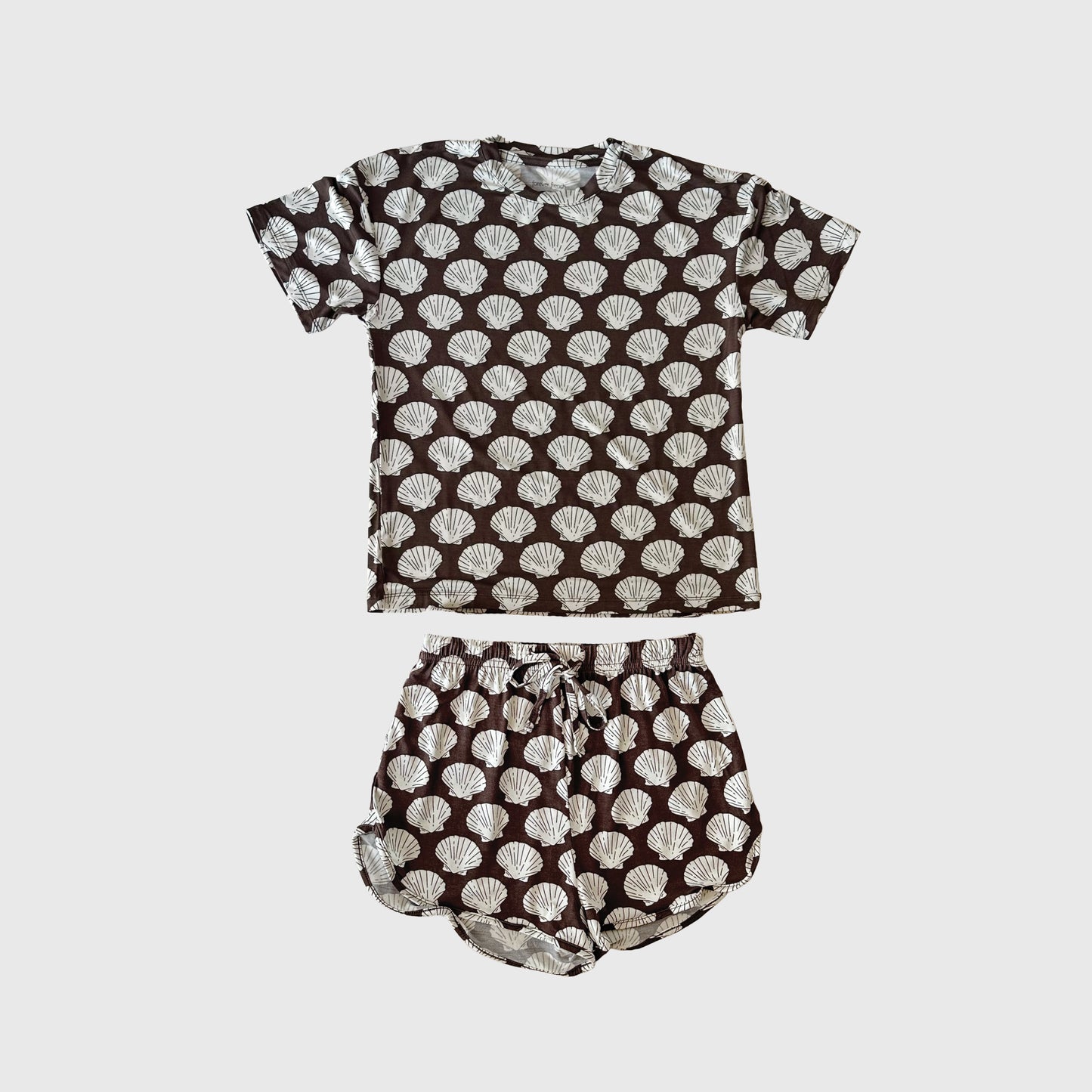 The Girl's Bamboo Short Set | Seashells from forever french baby features a dark short-sleeve shirt and shorts with a white seashell pattern, made from breathable bamboo sleepwear fabric, displayed flat on a white background.