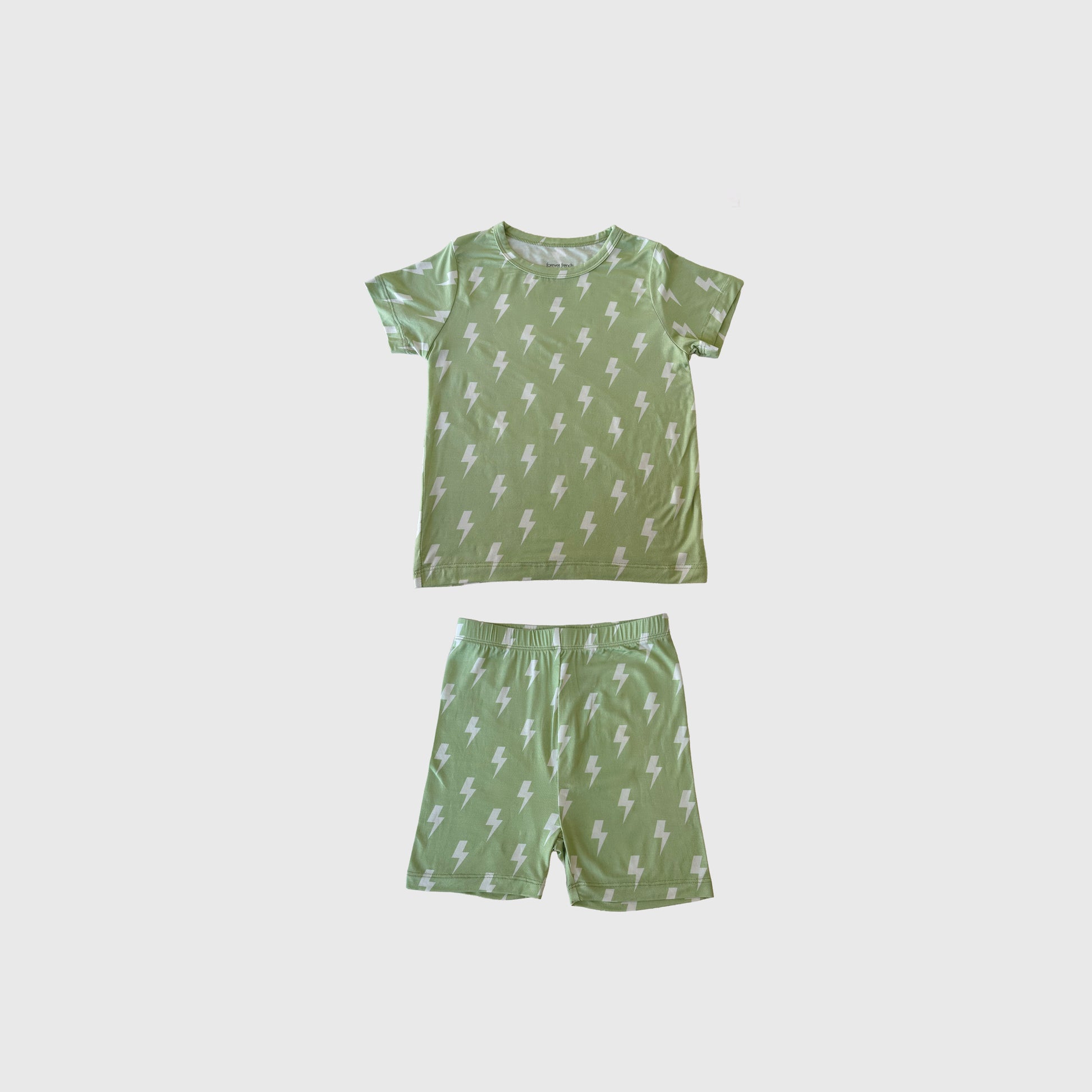 The Bamboo Short Set | Flash by forever french baby features green bamboo pajamas with a white lightning bolt print. This short-sleeve t-shirt and shorts set offers breathable comfort and is displayed on a plain white background.