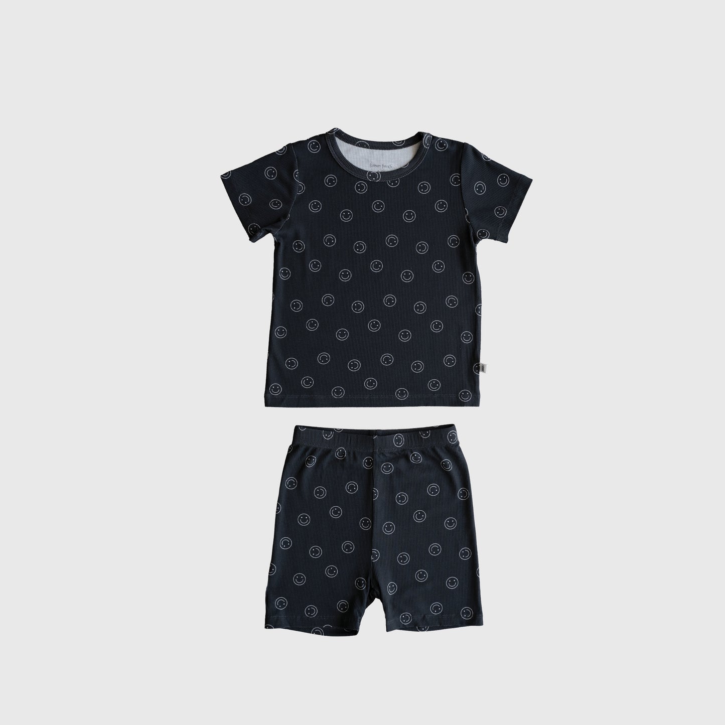 The Bamboo Short Set | Smiley Ribbed by forever french baby features a dark blue short-sleeve shirt and shorts with small white circles, made from soft bamboo pajama fabric and shown flat on a light gray background.