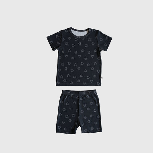The Bamboo Short Set | Smiley Ribbed by forever french baby features a dark blue short-sleeve shirt and shorts with small white circles, made from soft bamboo pajama fabric and shown flat on a light gray background.