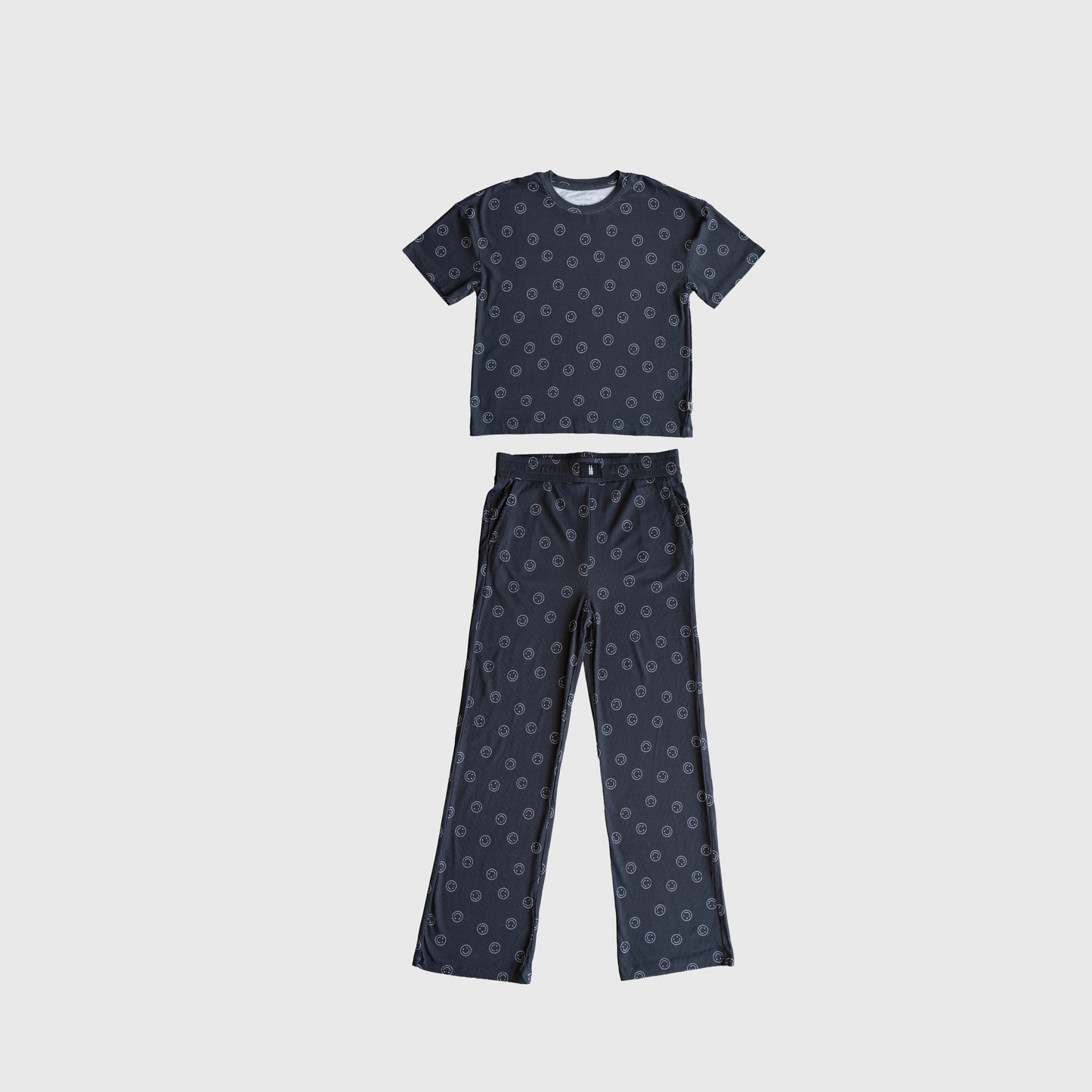 The forever french baby Child Boxy Tee Lounge Set | Smiley Ribbed features a matching short-sleeve shirt and long pants in dark blue with a small circular print, made from breathable bamboo, laid flat on a light background.