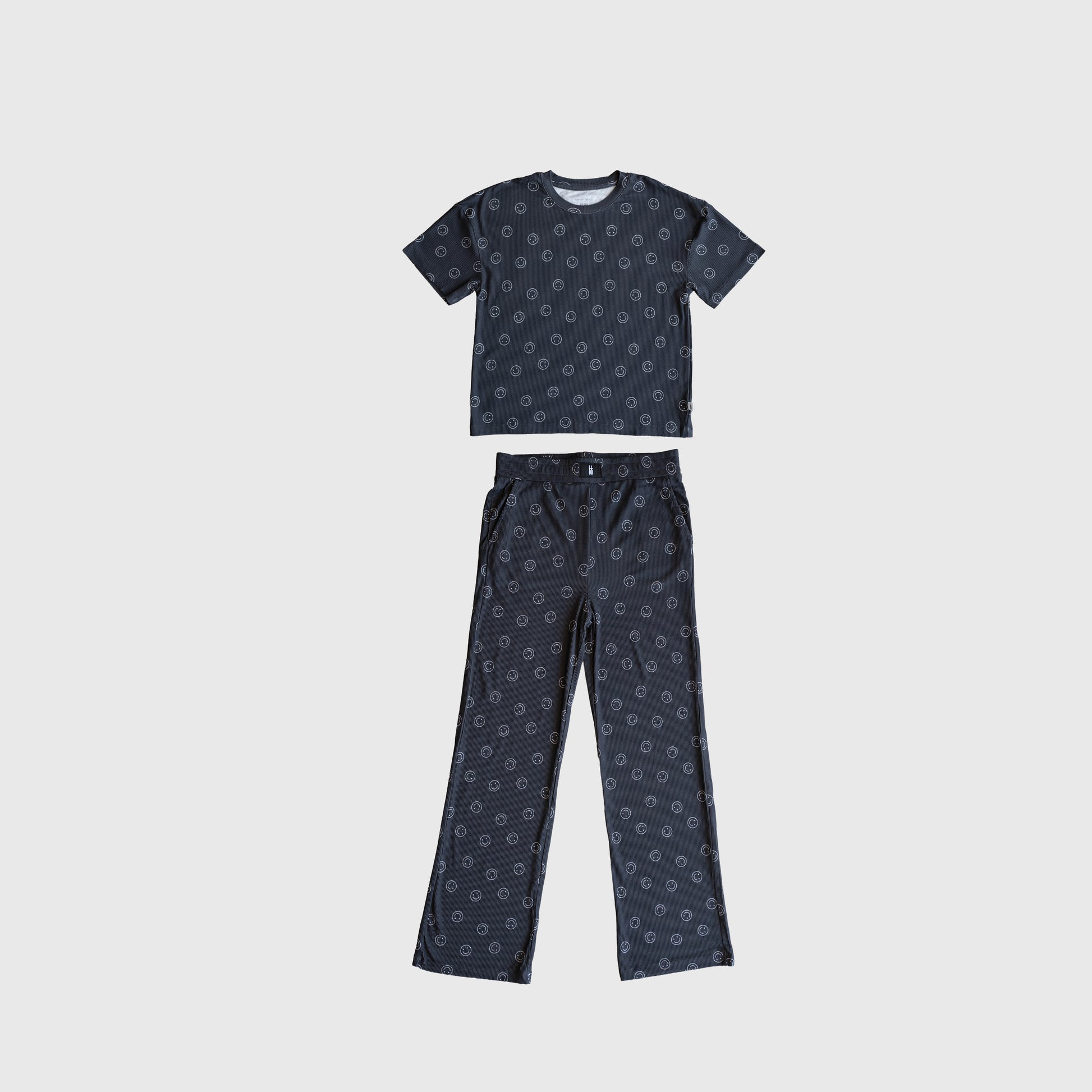 The forever french baby Child Boxy Tee Lounge Set | Smiley Ribbed features a matching short-sleeve shirt and long pants in dark blue with a small circular print, made from breathable bamboo, laid flat on a light background.