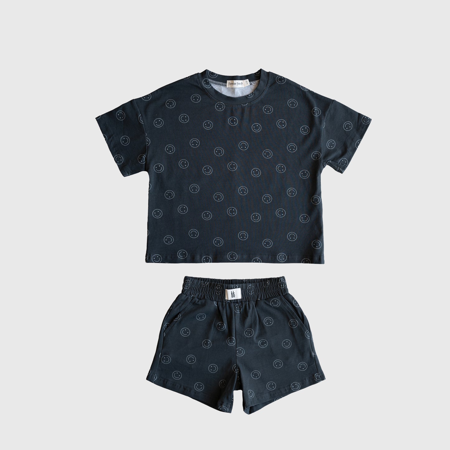 The forever french baby Child Short Set | Smiley features a dark cotton blend top and matching shorts with a subtle circular pattern, shown on a light gray background.