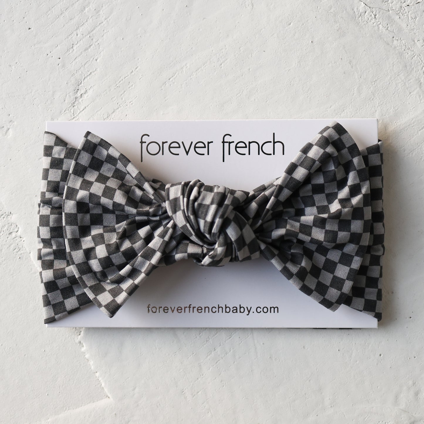 The Bamboo Head Wrap | Street Micro Check by forever french baby is shown on a branded card with "foreverfrenchbaby.com" against a textured white background. The headband features a black and white checkered pattern.