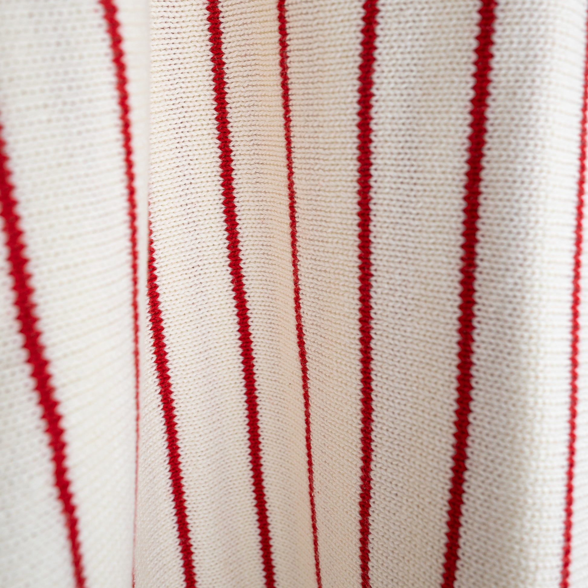 Close-up of the forever french baby Knit Ruffle Romper | Picnic Pinstripe, featuring soft white 100% cotton knit with red vertical stripes. The texture and pattern highlight its comfort and quality—perfect for stylish little ones.