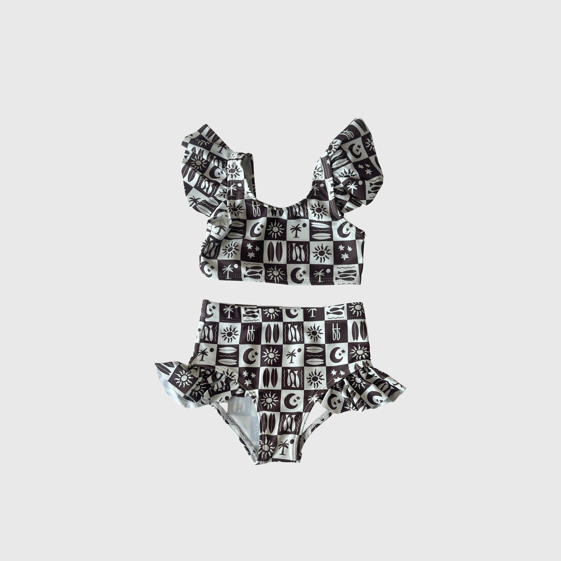 The Girl's Two Piece Swimsuit | Summer Check by forever french baby features ruffled straps and waist with suns, moons, eyes, and celestial symbols on a black and white checkered design—a stylish pick in kids swimwear.