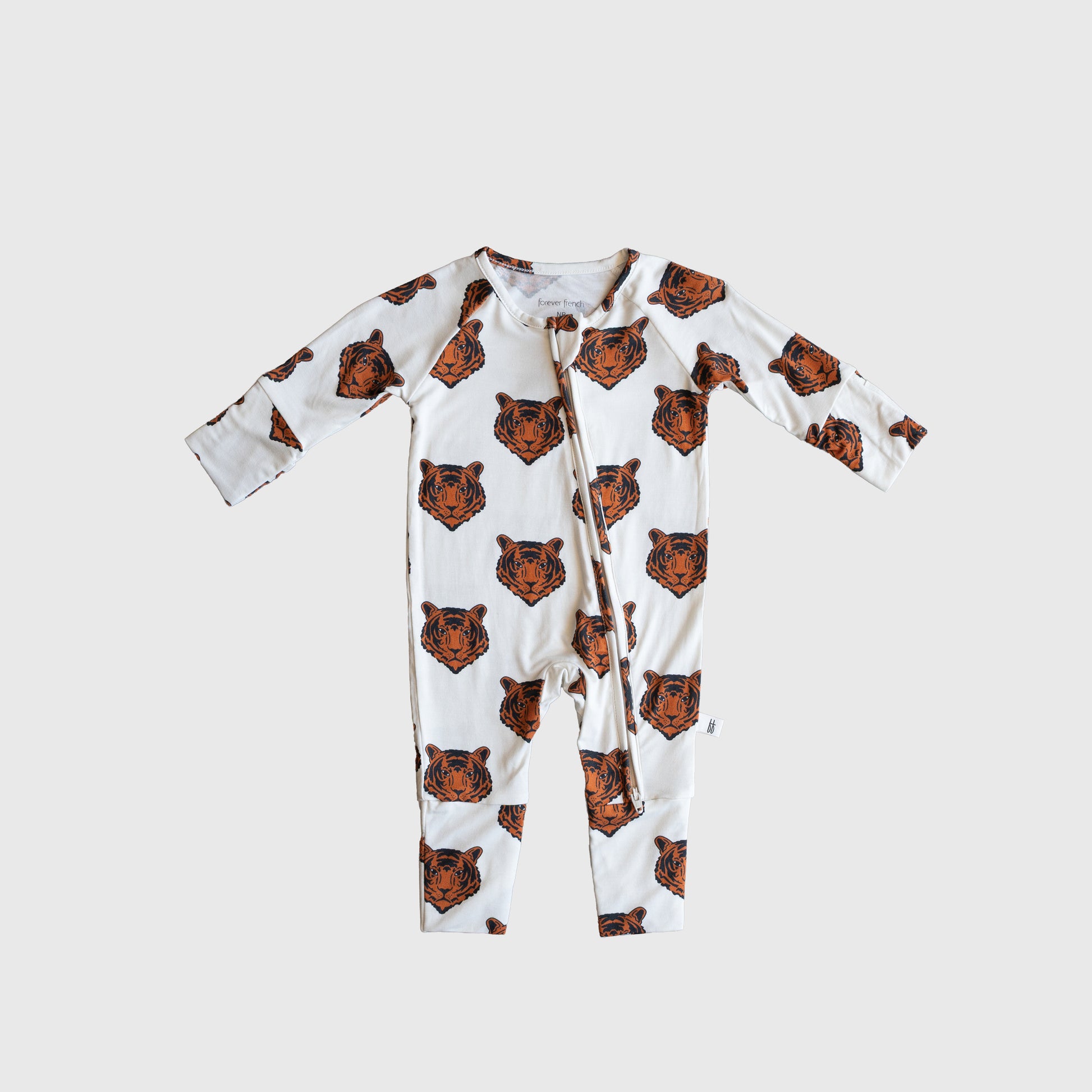The Bamboo Zip Pajamas | Tigers by forever french baby features a white base with orange tiger faces, crafted from hypo-allergenic material for gentle comfort.