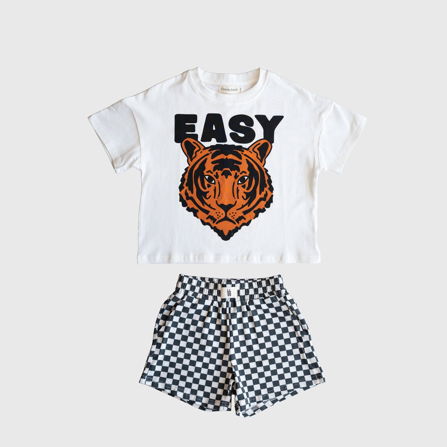 The forever french baby Child Short Set | Easy Tiger features a white cotton-blend tee with "EASY" and an orange tiger face, paired with black-and-white checkered shorts, displayed on a light background.