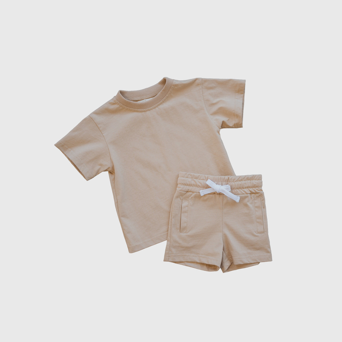 The forever french baby Child Short Set | Toffee features a beige short-sleeve t-shirt and matching cotton shorts with an elastic waistband and white drawstring, shown on a plain white background—ideal comfortable play clothes for children’s everyday wear.