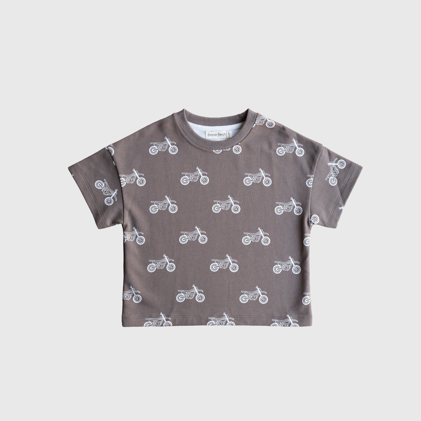 The French Terry Short Set | Dirt Bike by forever french baby features a kids’ short-sleeved, brownish-grey t-shirt with a white motorcycle pattern and matching shorts, shown on a plain white background.