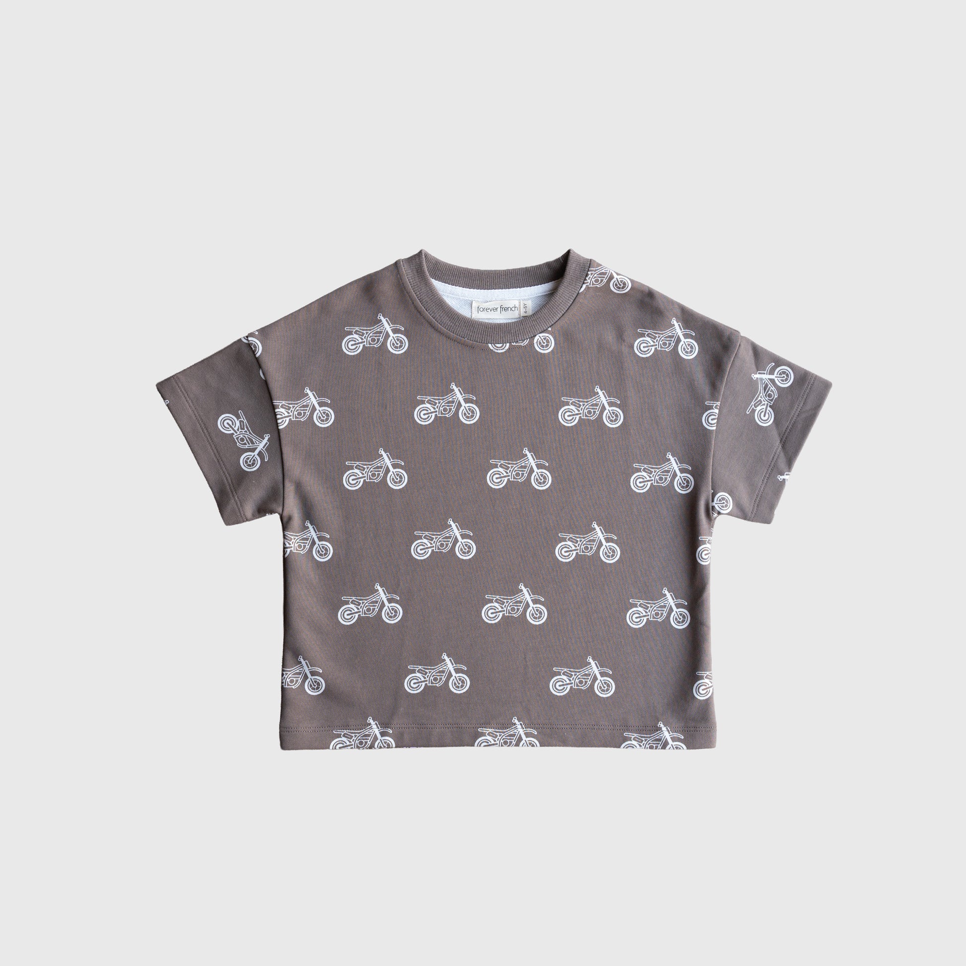 The French Terry Short Set | Dirt Bike by forever french baby features a kids’ short-sleeved, brownish-grey t-shirt with a white motorcycle pattern and matching shorts, shown on a plain white background.