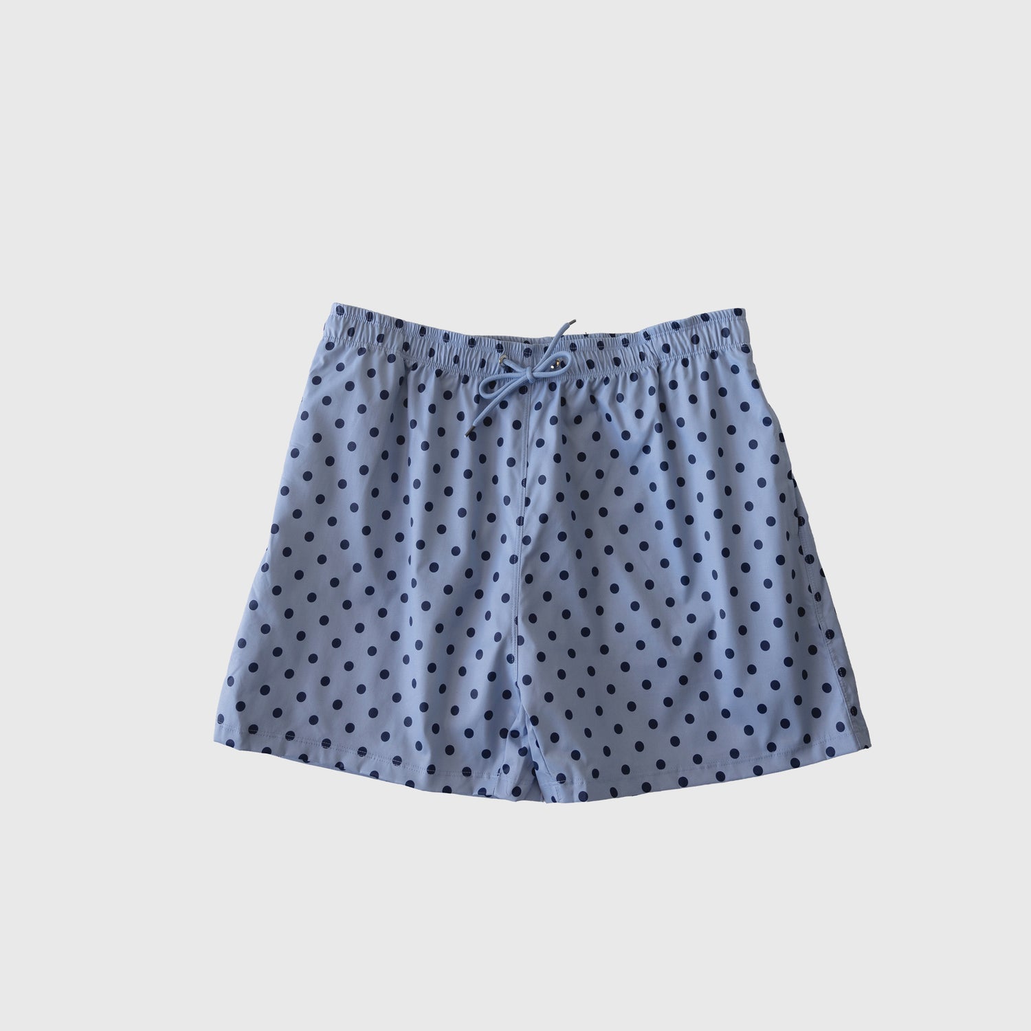 The Men's Board Short | Sully by forever french baby features light blue fabric, an elastic waistband with drawstring, and blue polka dots, shown on a white background. Pair it with items from our matching swim collection.