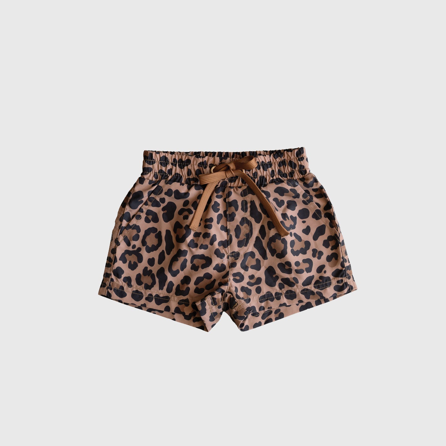 The *PRE-ORDER* Child Board Short | Leopard by forever french baby features a stylish brown leopard print, elastic waistband, and front tie bow—perfect for warm days. Shown on a plain white background.