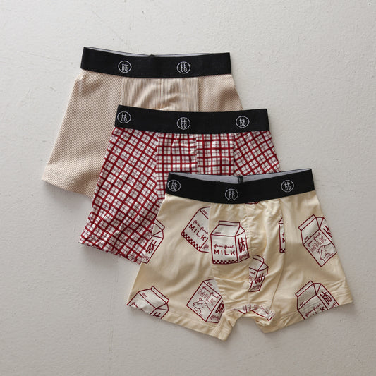 Three pairs of men’s Bamboo Boxers (3 Pack) by forever french baby—featuring window pane, milk carton print, and ribbed cream styles—are displayed on a white surface. Each has a black waistband with the brand’s white circular logo.